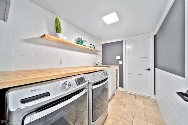 washroom featuring cabinets, separate washer and dryer, crown molding, and sink