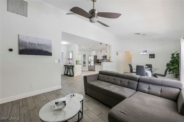 living room featuring ceiling fan, light hardwood / wood-style flooring, and lofted ceiling