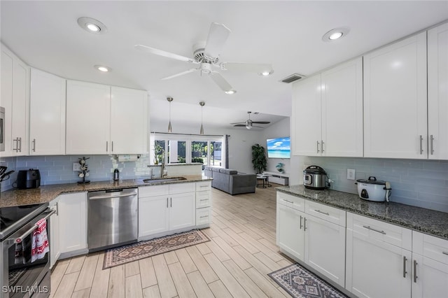 kitchen featuring dark stone counters, white cabinets, sink, light hardwood / wood-style flooring, and stainless steel appliances