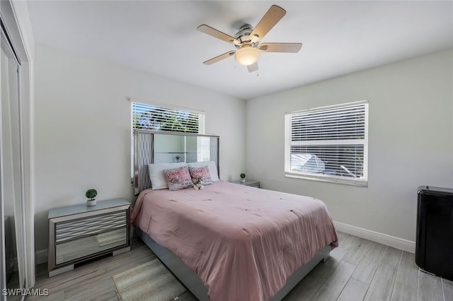 bedroom with ceiling fan, light hardwood / wood-style floors, and a closet