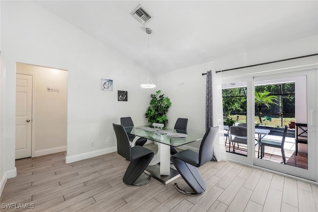 dining room with light wood-type flooring and high vaulted ceiling