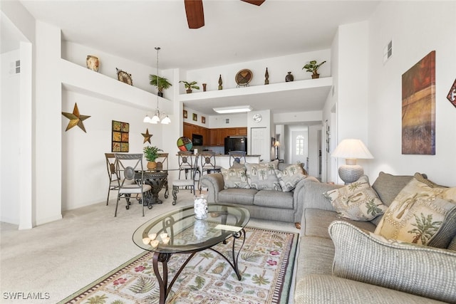 carpeted living room featuring ceiling fan with notable chandelier