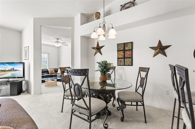 carpeted dining space featuring ceiling fan with notable chandelier and vaulted ceiling