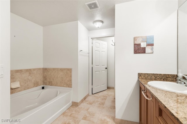 bathroom with a bathtub, vanity, and a textured ceiling