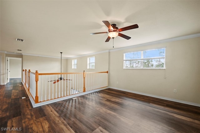 spare room featuring dark wood-style floors, visible vents, crown molding, and baseboards