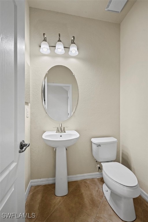 bathroom featuring tile patterned flooring, toilet, and baseboards