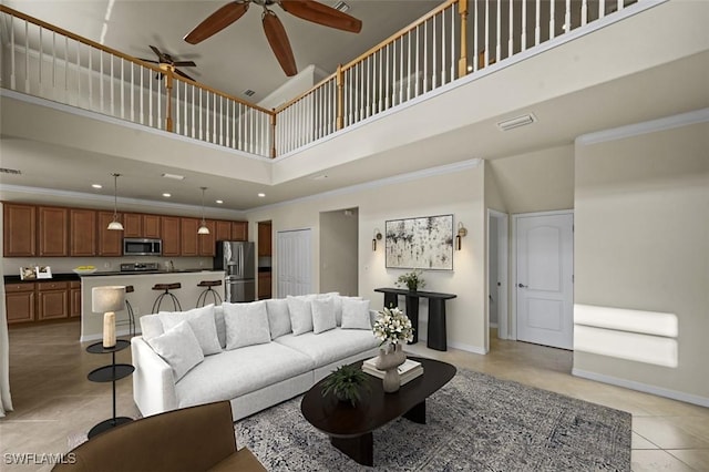 living room featuring light tile patterned floors, baseboards, ornamental molding, a high ceiling, and recessed lighting