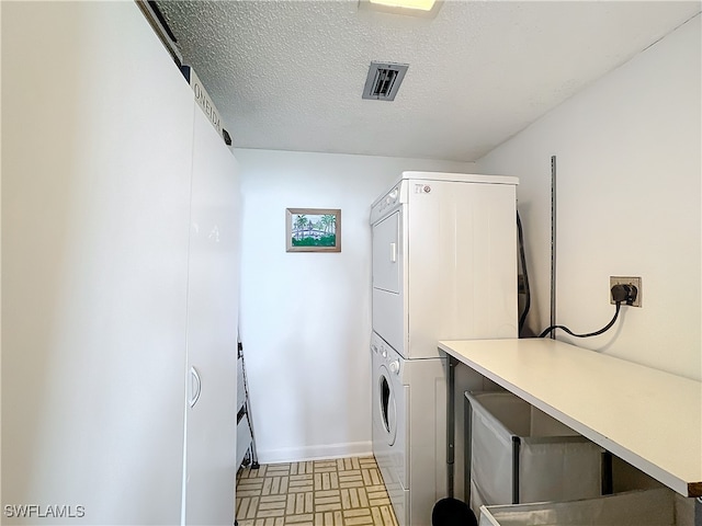 washroom with a textured ceiling and stacked washing maching and dryer