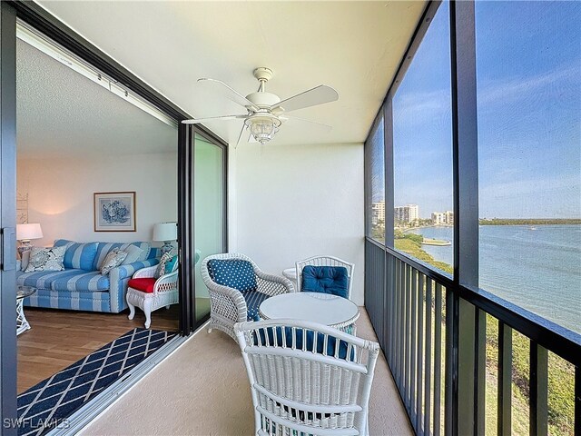 sunroom / solarium featuring ceiling fan and a water view