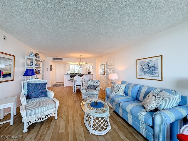 living room with hardwood / wood-style flooring, a textured ceiling, and a chandelier