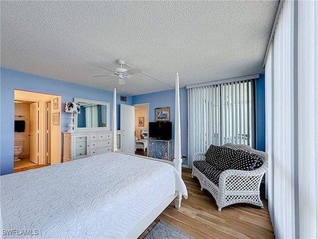 bedroom featuring ceiling fan, ensuite bathroom, light wood-type flooring, and a textured ceiling