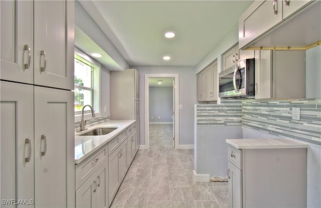 kitchen with backsplash, gray cabinetry, and sink