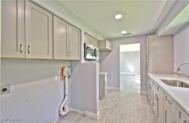 kitchen with light tile patterned floors, light stone counters, and sink