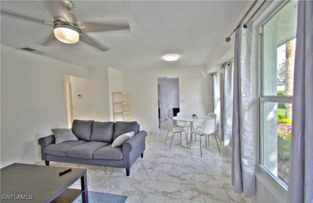 living room featuring ceiling fan and a textured ceiling