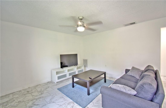 living room featuring ceiling fan and a textured ceiling