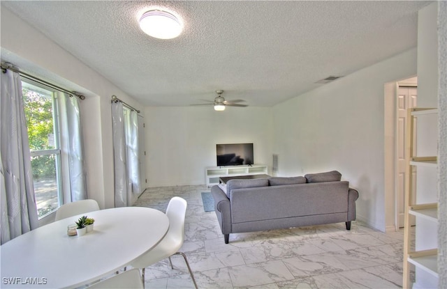 living room with ceiling fan and a textured ceiling