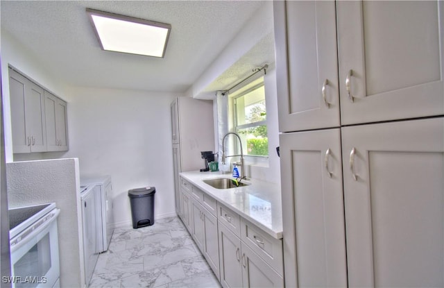 kitchen featuring electric range, gray cabinetry, sink, and a textured ceiling