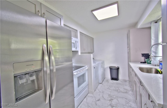 kitchen featuring white appliances, washer and clothes dryer, gray cabinetry, and sink