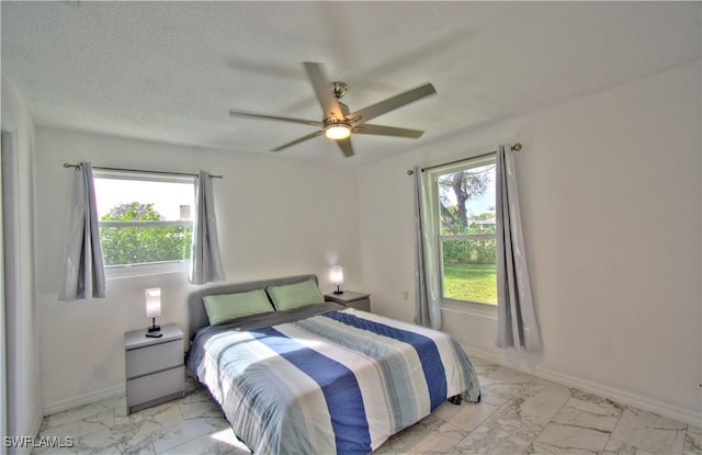 bedroom with ceiling fan, a textured ceiling, and multiple windows