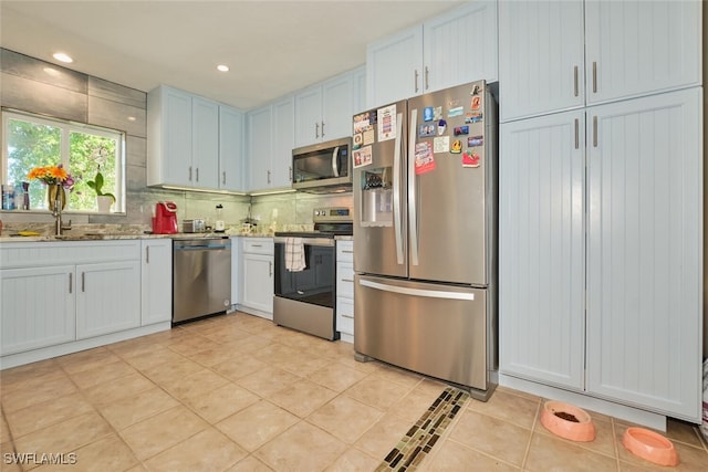 kitchen featuring tasteful backsplash, sink, white cabinets, and appliances with stainless steel finishes