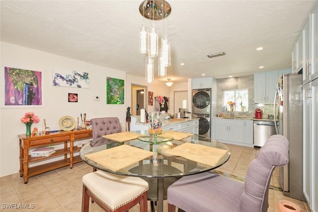 tiled dining area featuring sink and stacked washer and clothes dryer