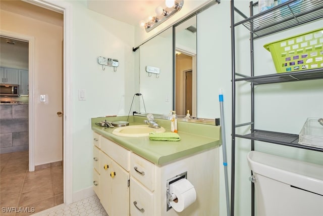 bathroom with tile patterned flooring, vanity, and toilet