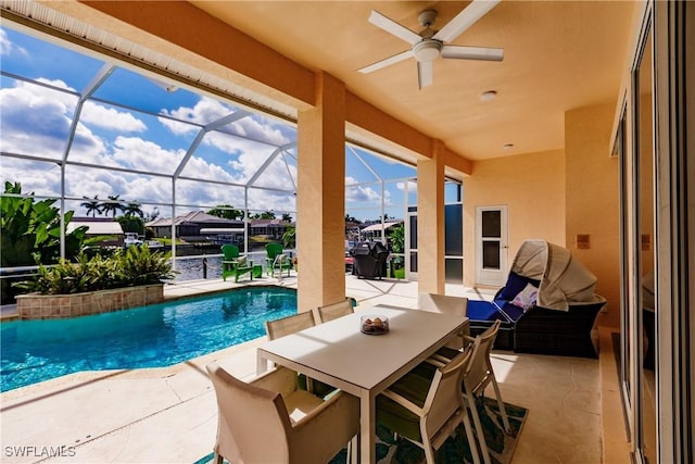 view of swimming pool featuring a patio, a water view, glass enclosure, and ceiling fan