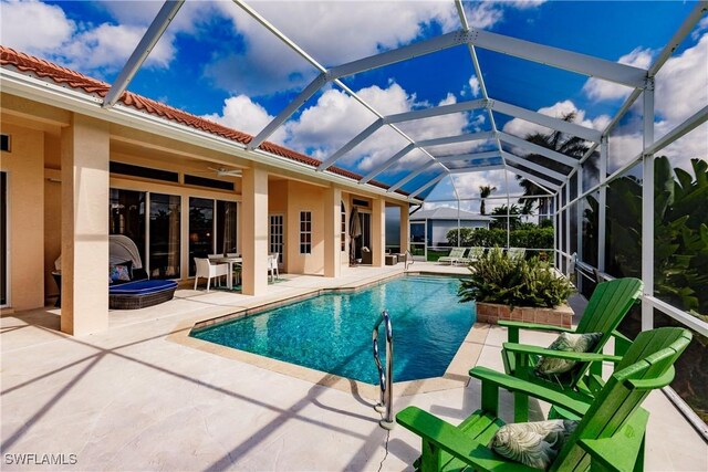 view of pool with glass enclosure, ceiling fan, and a patio