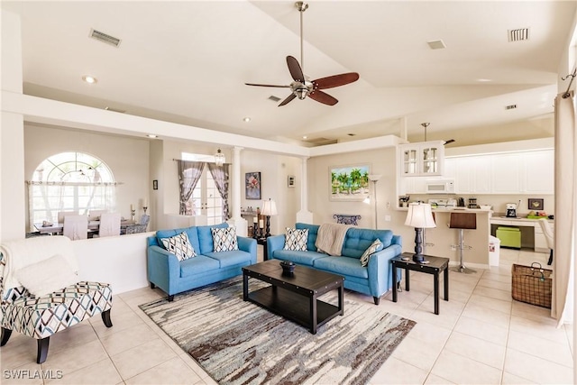 living room with decorative columns, ceiling fan, light tile patterned floors, and vaulted ceiling