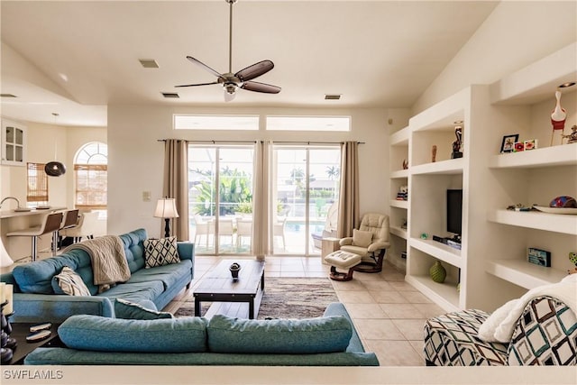 living room featuring built in shelves, ceiling fan, lofted ceiling, and light tile patterned floors