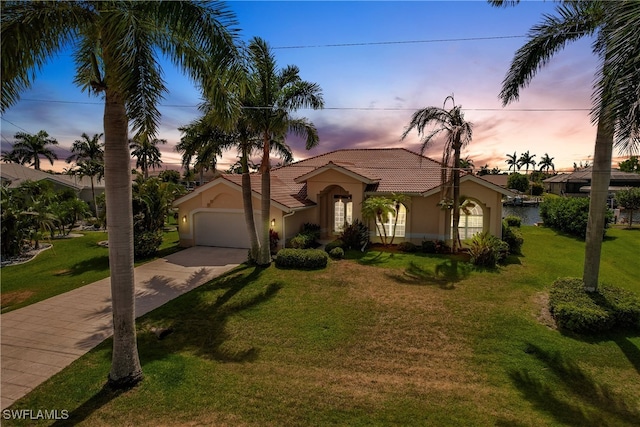 mediterranean / spanish-style house with a garage and a lawn