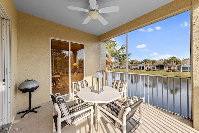 sunroom / solarium with ceiling fan and a water view