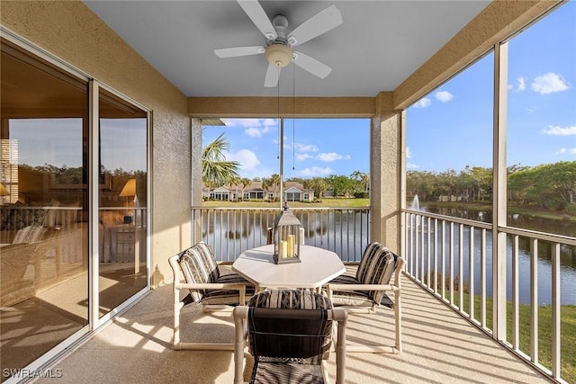 sunroom / solarium featuring ceiling fan and a water view