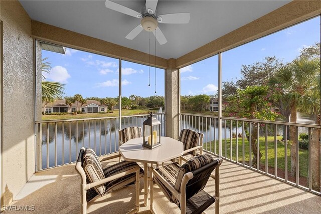 sunroom featuring ceiling fan and a water view