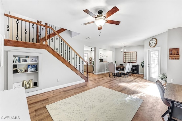 living room with hardwood / wood-style floors and ceiling fan with notable chandelier