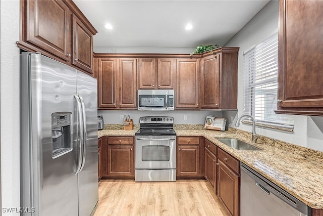 kitchen featuring light stone countertops, sink, stainless steel appliances, and light hardwood / wood-style floors