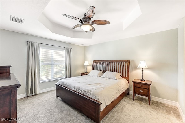 carpeted bedroom featuring a raised ceiling and ceiling fan