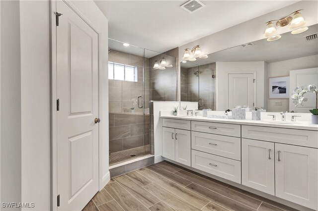 bathroom featuring a shower with door and vanity