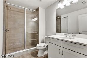 bathroom with a shower with door, vanity, and toilet