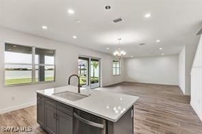 kitchen featuring sink, a center island with sink, stainless steel dishwasher, a chandelier, and light wood-type flooring