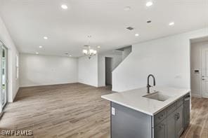 kitchen with a chandelier, a center island with sink, light hardwood / wood-style floors, and sink