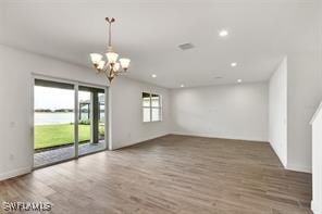 unfurnished room with an inviting chandelier and dark wood-type flooring