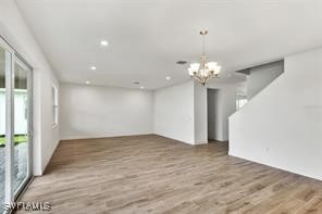 unfurnished living room with wood-type flooring and a chandelier