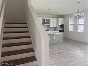 staircase with hardwood / wood-style flooring, a chandelier, and sink