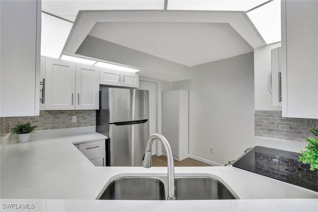 kitchen featuring sink, stainless steel fridge, decorative backsplash, and white cabinetry