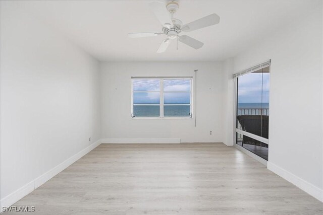 spare room featuring light wood-type flooring, a water view, plenty of natural light, and ceiling fan