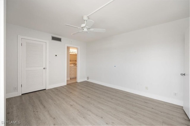 unfurnished bedroom featuring connected bathroom, a closet, light hardwood / wood-style flooring, and ceiling fan