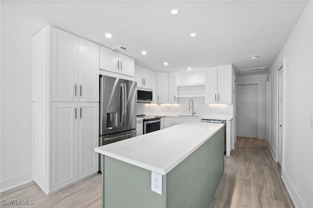 kitchen featuring sink, a center island, light hardwood / wood-style floors, white cabinets, and appliances with stainless steel finishes