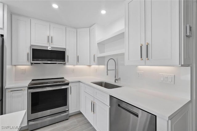 kitchen with white cabinets, appliances with stainless steel finishes, light hardwood / wood-style flooring, and sink