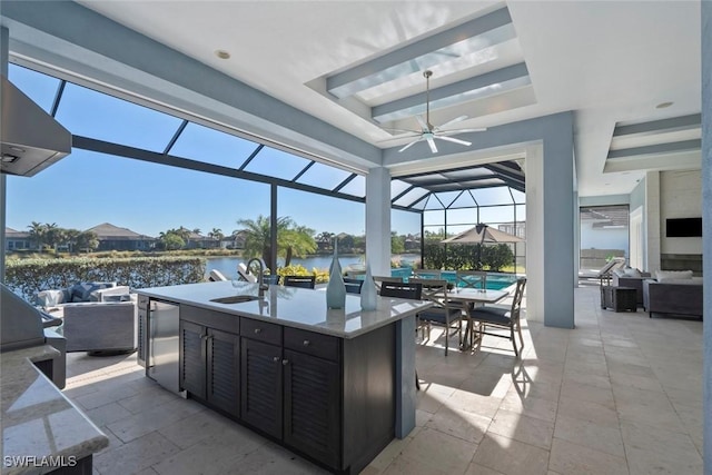 view of patio with a water view, an outdoor wet bar, ceiling fan, a lanai, and exterior kitchen